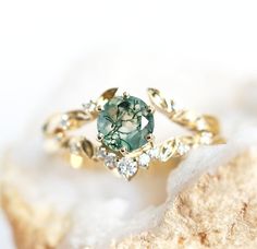 a close up view of a ring with a green stone in the middle and white stones around it