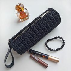 the contents of a black purse, lipstick, eyeliners and an empty bottle