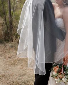 a bride and groom standing in the woods