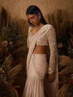 Dusty pink layered Saree with attached pre-draped and pre-stitched pallu featuring a hand embellished floral zardozi and mother of pearl border. Paired with a matching embellished blouse with a sweetheart neck & sheer sleeves, and a tie back.From Shloka Khialani 's Serendipity collection.DELIVERY TIMEPlease allow 6-8 weeks for your outfit to arrive.FABRIC DETAILSGeorgette, Net, CrepeProfessional cleaning only. Shloka Khialani, Indian Fits, Asian Couture, Pearl Border, Sarees Bridal, Saree Gowns, Drape Sarees, Trendy Outfits Indian, Fashion Sarees