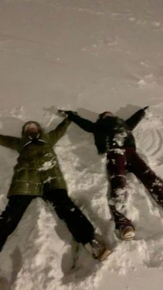 two people laying in the snow with their arms around each other