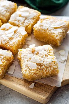 several pieces of cake on a cutting board with coconut flakes and powdered sugar