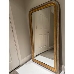 a large gold framed mirror sitting on top of a white table next to a doorway