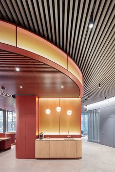 the interior of an office building with red walls and wooden ceilinging is lit by round lights