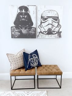 two star wars paintings hang on the wall next to a bench with pillows in front of it