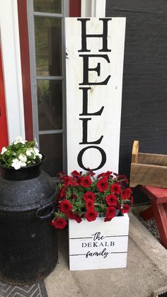 a sign that says hello on it next to some flowers and a potted plant