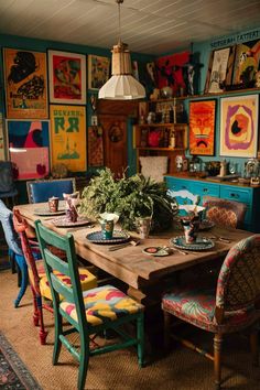 a dining room table with colorful chairs and pictures on the wall behind it in an eclectic style