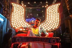 a man sitting on top of a red chair in front of a large light sculpture