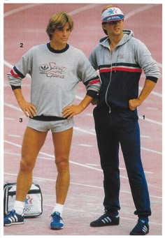 two men standing next to each other on a track with their hands on their hips