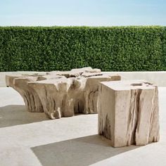 two pieces of wood sitting on top of a cement floor next to a green hedge