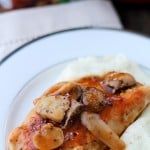 a white plate topped with mashed potatoes and meat covered in mushroom gravy