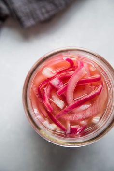 a jar filled with sliced red onions on top of a table