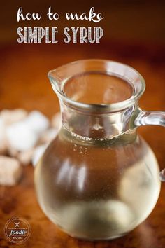 a glass pitcher filled with liquid sitting on top of a wooden table next to marshmallows