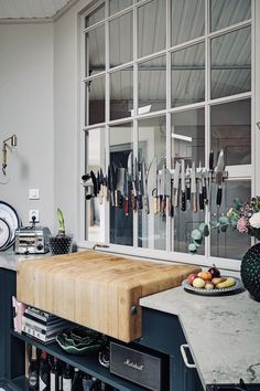 a kitchen counter with a wooden cutting board on top of it next to a window