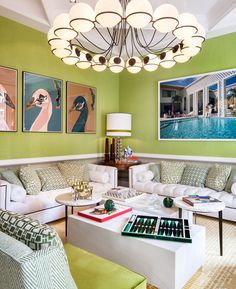 a living room with green walls and white couches in front of a chandelier