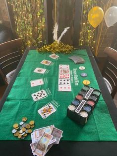 a green table topped with lots of cards and other items next to some gold balloons