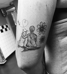 a woman with a tattoo on her arm is sitting next to a dog and flowers