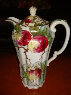 a white and red vase sitting on top of a wooden table