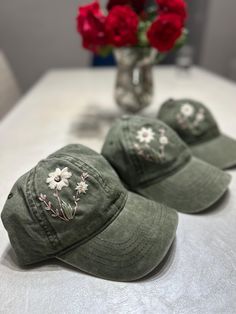 three hats sitting on top of a white table next to a vase with red flowers