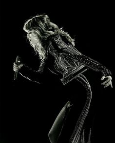 a black and white photo of a woman in a dress holding a microphone with her right hand