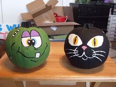 two pumpkins with faces painted on them are sitting on a table in front of boxes