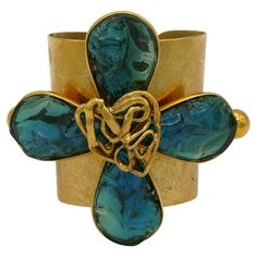 YVES SAINT LAURENT by ROBERT GOOSSENS vintage rare textured gold tone cuff bracelet featuring a massive stylized four clover centrepiece embellished with irregular shaped acqua blue resin petals and an openwork heart. Embossed YVES SAINT LAURENT RIVE GAUCHE. Made in France. Indicative measurements : inner measurements approx. min. 5.5 cm (2.17 inches) x 4.2 cm (1.65 inches) / inner measurements max. approx. 6.2 cm (2.44 inches) x 5 cm (1.97 inches) / centrepiece approx. 9.2 cm (3.62 inches) x 11 Resin Petals, Key Bracelet, Vintage Jewelry Bracelets, Rive Gauche, Jewelry Inspo, Gold Texture, Gold Tone Metal, Cuff Bracelet, Made In France