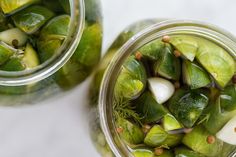 two jars filled with pickles on top of a table