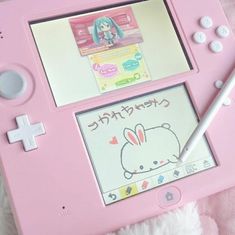 a pink nintendo wii game system with an anime character drawn on the screen and a white pen