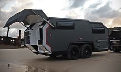 an off - road camper is parked next to a black truck on the beach