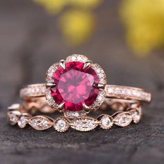 a close up of two rings with a red stone in the middle and white diamonds around it