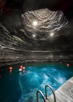 the inside of a cave with blue water and red balls floating on it's surface