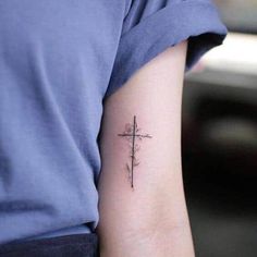 a small cross tattoo on the arm