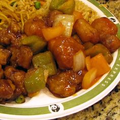 a white plate topped with meat and veggies next to noodles on a table