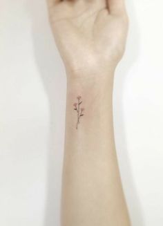 a woman's wrist with a small flower tattoo on the left side of her arm