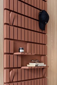 a shelf with books, glasses and a hat on it next to a wooden wall