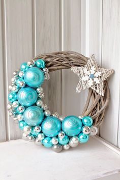 a wreath with ornaments hanging on the wall next to a star and snowflake