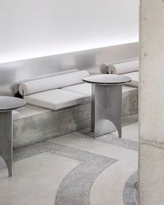 two tables sitting next to each other in a room with white walls and concrete flooring