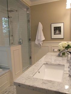 a bathroom with marble counter tops and white towels hanging on the shower door, along with a sink