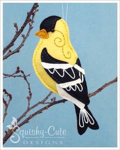 a yellow and black bird hanging from a tree branch with the words squishy cute designs on it