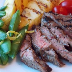 steak, green beans and tomatoes on a white plate