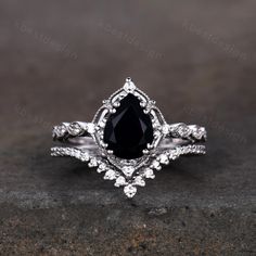 a black and white diamond engagement ring set on top of a stone surface with diamonds around it