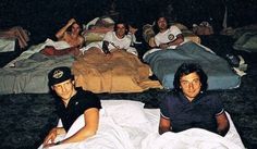 group of men laying on the ground in front of sleeping bags and blankets at night