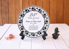 a black and white plate sitting on top of a table next to a small cactus