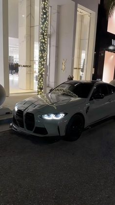 a white sports car parked in front of a building at night with christmas lights on the windows