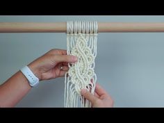 someone is working on a macrame weaving project with white yarn and wooden dows