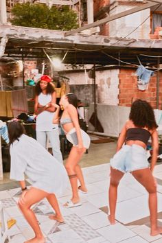 two women in bathing suits are dancing on the sidewalk while others watch from behind them