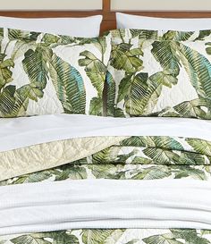 a bed with green and white leaves on it