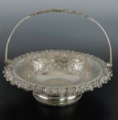 an ornate silver basket with handles on a table