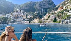 two women sitting on the back of a boat looking out over the water at boats