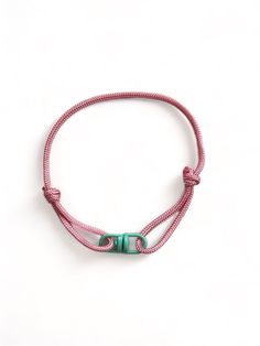 a pink and green bracelet with two beads on it's end, sitting against a white background